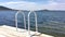 Terrace pier with a view on sea and sunset. Steel swimming ladder in a sunlight.