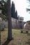 Terrace with trees and benches next to a boundary wall of a castle with a bridge in the distance