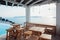 Terrace under the roof with wooden tables and chairs overlooking the sea next to the swimming pool in Santorini