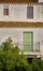 Terracotta tiled, white mediterranean house, pale green blind and wooden windows.