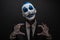 Terrible clown and Halloween theme: Crazy blue clown in black suit isolated on a dark background in the studio