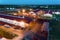 The territory of an industrial plant. Large hangars with a red roof. Aerial view, night shooting