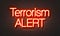 Terrorism alert neon sign on brick wall background.