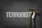 Terrorist text on blackboard with businessman hand holding ammunition