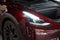 Tesla car model Y in cherry red color in Studio, electric vehicle in showroom, li-ion 4680 battery, alternative energy development