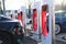 Tesla passenger electric cars, modern vehicles replenishes battery at charging station, alternative energy development concept,