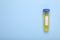 Test tube with liquid on light blue background, top view and space for text. Kids chemical experiment toy