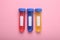 Test tubes with colorful liquids on pink background, flat lay. Kids chemical experiment set