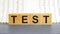 TEST word made with building blocks. Test on wooden cubes on grey notepad. Business concept