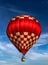 Tethered red and white checkered hot air balloon at festival