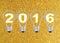 Text 2016 in lightbulb on gold glitter background