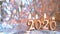 Text 2020 golden candles burning. Blurred silver background. Copyspace. Merry christmas and Happy New Year. Selective