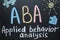 Text ABA Applied behavior analysis and drawings on blackboard