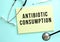 The text ANTIBIOTIC CONSUMPTION is written in a yellow pad that lies next to the stethoscope on a blue background.