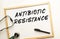 The text ANTIBIOTIC RESISTANCE is written on a white office board. Nearby is a stethoscope