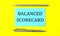 Text BALANCED SCORECARD on the blue sticker on the yellow background