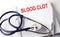 Text BLOOD CLOT on a white background with stethoscope. Medical