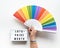 Text box with LGBTQ pride month text . Hand holds. rainbow fan. Ribbon with rainbow design on wrist. Flat lay, top view