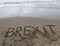 Text BREXIT on the sand of the sea waiting to be erased by the w