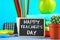 Text chalk on a chalkboard: Happy Teacher`s Day. School supplies, office, books, apple.