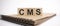 Text CMS on the wooden cubes and craft colored notepad on the white background