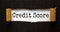 The text `credit score` appearing behind torn black paper. Business concept
