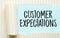 The text Customer Expectations appearing behind torn white paper