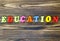 Text `education` of plastic colored magnetic letters on wooden background.