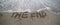 text THE END that is deleted by the sea wave on the sandy beach