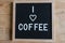 Text in english spelling I love Coffee with a heart on black felt board in a wooden frame. Letter Board on wood background. A