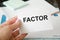 The text factor is written on a white card held by a person. risk factor for business loss, illness