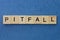 text on gray word pitfall in small wooden letters with black font