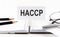 Text HACCP on paper card,pen, pencils, glasses,financial documentation on table - business concept