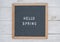 Text Hello spring on wooden letter Board in white letters on grey background