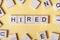 Text of HIRED on cubes. Wooden abc