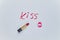 Text KISS drawing and trace of kiss by red lipstick on white sheet