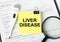 The text Liver Disease is written on a yellow sticker next to the magnifying glass and electronic thermometer