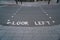 Text look left in white letters on asphalt of street in London