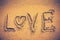 Text LOVE handwritten on seashore sand. Vignette and vintage ton