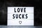 Text love sucks in a lightbox