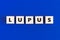 Text LUPUS on wooden cubes on blue background. Autoimmune disease, medicine concept.