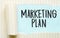 The text MARKETING PLAN appearing behind torn white paper