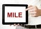 Text MILE on tablet display in businessman hands on the white bakcground. Business concept