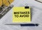 Text Mistakes To Avoid on a yellow sticker that is in a folder with documents and a blue metal pen