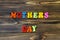 Text `mothers day` of plastic colored magnetic letters on wooden background