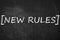 Text NEW RULES written on chalkboard
