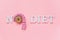 Text No diet and abstract funny face of woman from donut with eyes and hair from centimeter tape on plate on pink background.