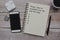 Text on notepad with cup of coffee, smart phone, music player and pen on wooden desk