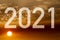 Text with the number of the year 2021 with a background image of the rising sun with clouds.