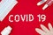 Text phrase Covid 19 on a red background with medicines, hand antiseptic, thermometer and protective mask